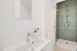 Un baño blanco con lavabo y ducha. en Le Coquet des Trois-Maisons avec parking privatif, en Nancy