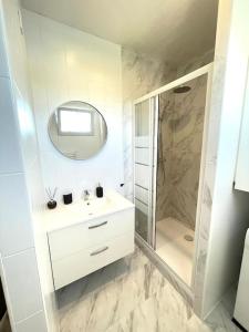 a white bathroom with a sink and a shower at Studio 10min Paris Centre I CDG in Drancy