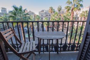 d'une table et de chaises sur un balcon avec des palmiers. dans l'établissement Barcelona Classic Plaza Real Apartments, à Barcelone