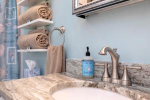 a bathroom with a sink and a mirror and towels at Tiny Luxury Studio GuestHouse in Deltaville in Deltaville