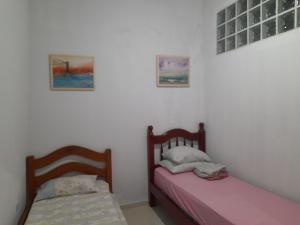 two beds in a room with white walls at Casa na praia em São Sebastião in São Sebastião