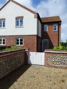 a brick house with a retaining wall and a fence at 3 double bed house with parking in Sheringham in Sheringham