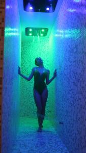 a woman is standing in a room with blue and green lights at The Hive Hotel in Rome