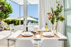 a white dining table with white chairs and flowers at Sea Escape in Cape Town +20 photos