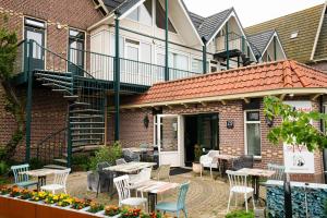 un patio con tavoli e sedie di fronte a un edificio di Hotel Orion a Kaag