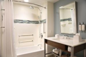 a bathroom with a white tub and a sink and a mirror at InterContinental New York Times Square by IHG in New York