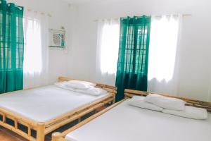 two beds in a room with green curtains at Hera Maria Hotspring Resort in Calamba