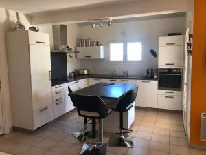 a kitchen with white cabinets and a table in it at Chambre à Marseillan Plage in Marseillan