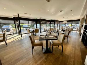 a restaurant with tables and chairs and windows at Parc Hôtel in Carvin
