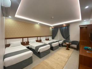 a hotel room with three beds and a room with chairs at فندق غالية احد in Al Madinah