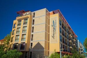 a tall yellow building with a sign on it at Harmony Suites Jungle - Apartment Veron in Sunny Beach