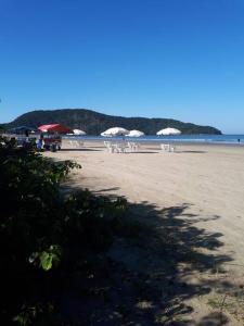 a beach with chairs and umbrellas on the sand at Confortável Casa na Praia do Indaiá Bertioga in Bertioga