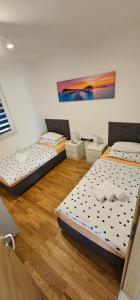 three beds in a room with wooden floors at Split/Podstrana Apartment ADRIA in Podstrana