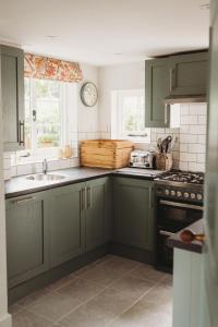 eine Küche mit grünen Schränken und einem Waschbecken in der Unterkunft Luxury Cottage with Garden in Bredon