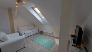 Una sala de estar con un sofá blanco y un televisor. en Zöldfa Apartmanház - Tetőtér, en Eger