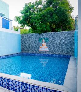 una piscina con una statua di una donna seduta in posizione meditativa di Le Springlynn Residency a Pondicherry