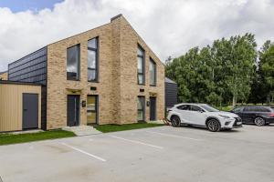 a brick house with a car parked in a parking lot at J7 Beržas 7A-1 in Palanga