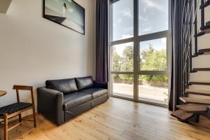 a living room with a leather couch and a large window at Uptown Lofts in Vilnius