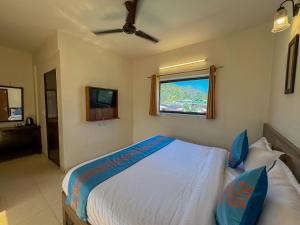 una camera da letto con un letto con cuscini blu e una finestra di Shelton Blu Resort Jim Corbett a Ramnagar