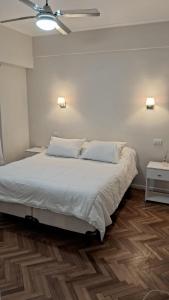 a bedroom with a bed with white sheets and wooden floors at Departamento Plaza Colón Yeyita in Mar del Plata +5 photos