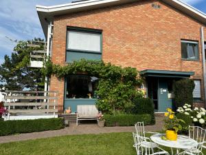 une maison avec une table et des chaises dans la cour dans l'établissement Hotel Bilderdijk, au Coq