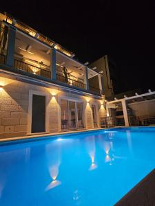 a swimming pool in front of a house at night at Villa LUX Apartments in Rogoznica