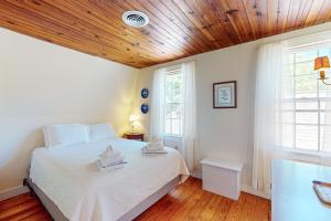 a bedroom with a bed with white sheets and wooden ceilings at Coastal Retreat in Centerville