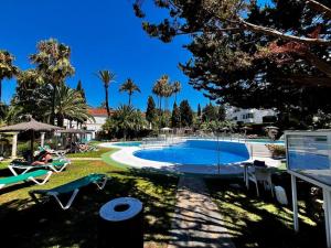 a large swimming pool in a resort with palm trees at Apartamento Lagarto in Sitio de Calahonda