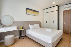 a bedroom with a white bed and a mirror at Otis Soho Saigon Balcony Apartment in Ho Chi Minh City