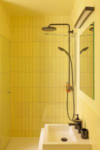 W wyłożonej żółtymi kafelkami łazience znajduje się umywalka i prysznic. w obiekcie Edgar Suites Marais - Temple w Paryżu +29 zdjęć