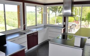 a kitchen with white cabinets and windows with a view at Gîte La Belle Aubrac in Saint-Côme-dʼOlt +10 photos