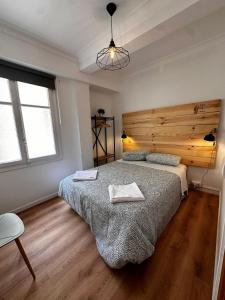 a bedroom with a large bed and a wooden wall at AtuaireHome Hostal en el centro de Burgos in Burgos