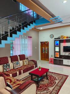 a living room with a couch and a staircase at "SMS" HOME STAy in Kushālnagar