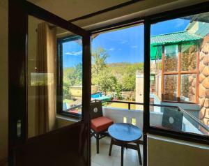 balcone con vista sulla piscina e tavolo di Shelton Blu Resort Jim Corbett a Ramnagar