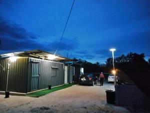 a man is standing outside of a house at night at Avina's Standard Room in Setiu +2 photos