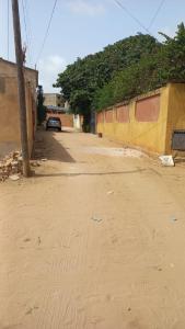 una calle vacía con un edificio amarillo y un coche en Studio tranquille à Saly Niakhniakhal, en Saly Niakh-Niakhal