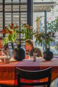 a man sitting at a table with flowers in vases at ViaVia Buenos Aires GuestHouse in Buenos Aires