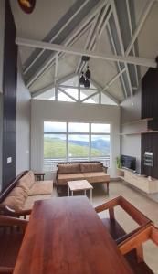 a living room with a table and a large window at Castra villas - Pool Villa in Parunthumpara in Vandiperiyār