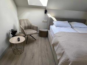 a small bedroom with a bed and a chair at Gamtos Slėnis kaimo turizmo sodyba in Bardinai
