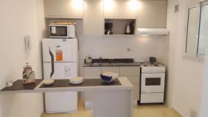 a kitchen with a white refrigerator and a microwave at Departamento a estrenar GALO VII in San Bernardo