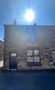 een bakstenen gebouw met de zon die op het dak schijnt bij Epworth Cottage in Crich