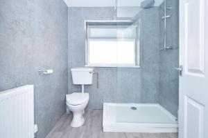 a bathroom with a toilet and a shower and a window at Holt House - By Sigma Stays in Crewe