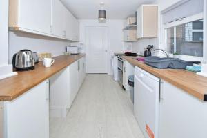 a kitchen with white cabinets and a wooden counter top at Holt House - By Sigma Stays in Crewe