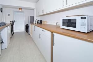 a kitchen with a counter top with a microwave at Holt House - By Sigma Stays in Crewe +28 photos