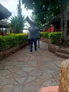 a man walking down a sidewalk with his arms out at Pine Breeze Getaway LUKENYA in Athi River +2 photos