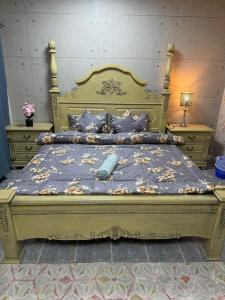 a large gold bed with a blue comforter and pillows at العين الهيلي مصباح ب 11 in Al Ain