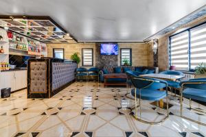 a bar with blue chairs and a tv in a room at РИМ Grand Hotel in Almaty