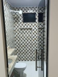 La salle de bains est pourvue de toilettes et d'une télévision murale. dans l'établissement Cattarino Dormitórios, à Cristalina