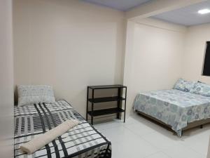 a bedroom with two beds and a night stand at Cattarino Dormitórios in Jardim