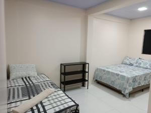 a bedroom with two beds and a tv in it at Cattarino Dormitórios in Jardim